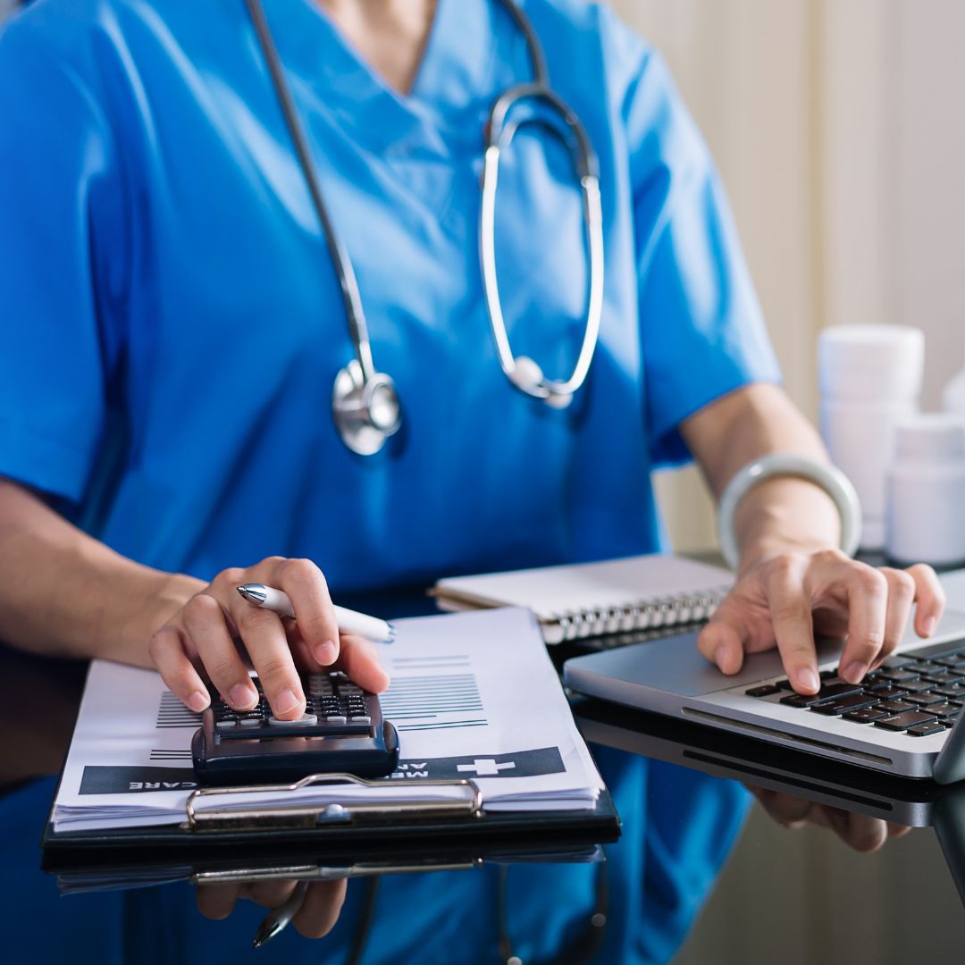Image showing healthcare worker using a calculator and a laptop.